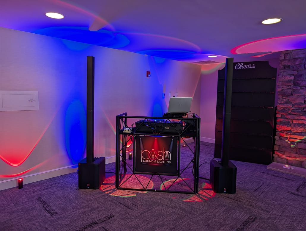 Professional corporate event DJ setup featuring low-profile audio equipment and a clean, cable-free aesthetic for a business function